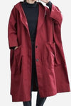 A person is wearing the looselyboho Burgundy One Size Fits All Oversized Water Resistant Windbreaker Jacket over a black top. This jacket features a relaxed fit with large pockets, a button closure, and an oversized hood. They have one hand near their face and the other in a pocket.