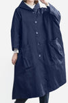 An individual is wearing a looselyboho Navy Blue One Size Fits All Oversized Water Resistant Windbreaker Jacket. The jacket includes a hood, large buttons, and two oversized front pockets. They are posing with one hand in a pocket against a plain background.